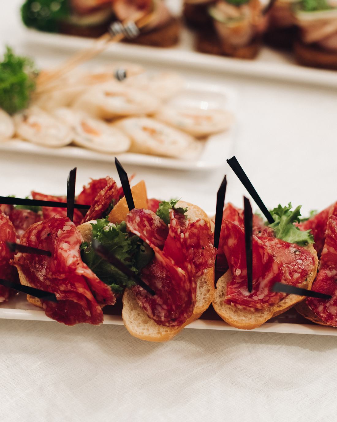 Aparador com canapés, wraps e bruschettas montados em travessas brancas